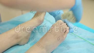 水疗沙龙的脱毛蜡。 美容师给妇女的腿`上蜡。 特写镜头。 从脚趾上脱毛。